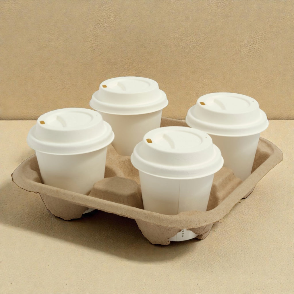 Four disposable coffee cups with lids in a cardboard holder on a beige background