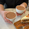 Mahalia Hot Chocolate in two cups with carrot cake 